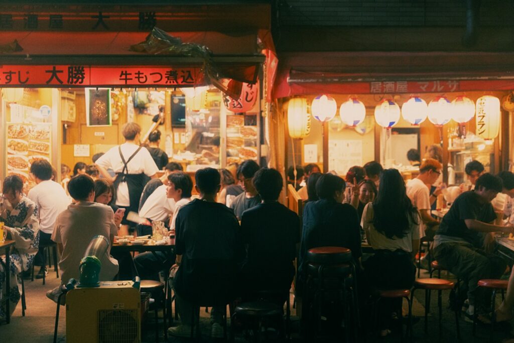 People eat outside a bustling japanese restaurant.