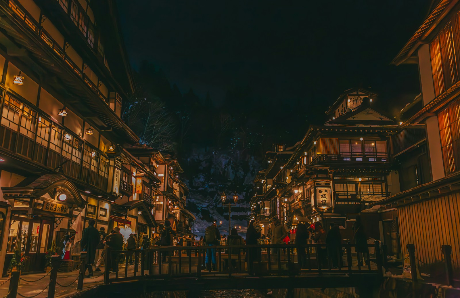 A city street at night with people walking on the sidewalk